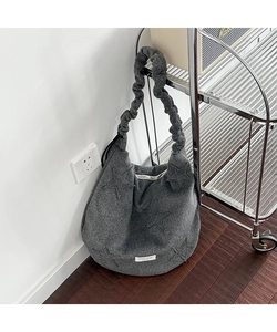 Detail of dark grey felt tote bag featuring star patch and ruffled scrunchie strap