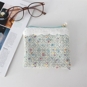 Close-up of blue tweed knit coin purse with lace trim and elegant pearl zipper detail