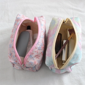 Detailed view of floral jacquard pouches with metal zippers and textured embroidery fabric