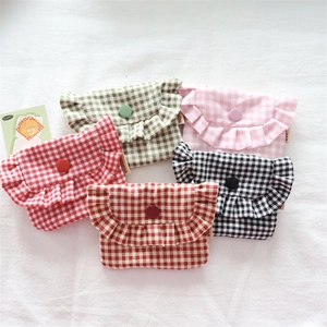 Detail of five plaid mini pouches with ruffle edges and snap buttons on white fabric