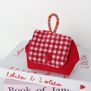 Detail of red houndstooth mini pouch with decorative button and colorful braided handle