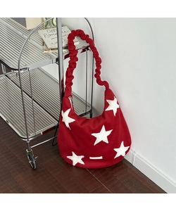 Detail of red wool shoulder bag featuring white star patch and ruched strap design