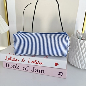 Detail view of a blue and white striped seersucker pencil case with metal zipper closure