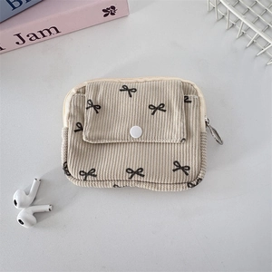 Macro detail of beige corduroy pouch with black bow print and metal zipper closure