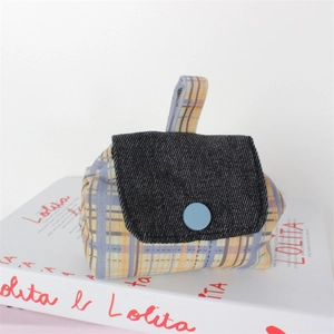 Close-up of a mini plaid canvas pouch with denim flap and light blue button detail
