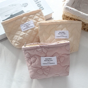 Detailed view of quilted makeup bags with ribbon patterns and smooth metal zippers