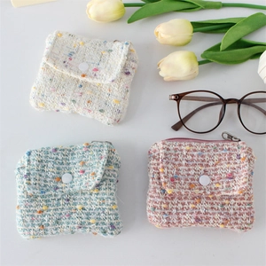 Detailed top view of three tweed coin purses in mint, pink, and beige with button flaps