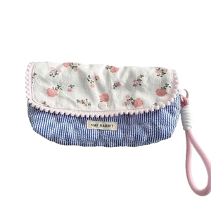 Floral quilted pencil case with blue stripes and pom-pom trim featuring a pink wrist strap
