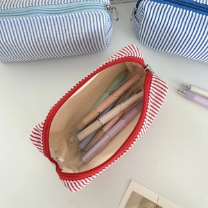 Detailed close-up of seersucker pencil case with striped fabric and metal ring zipper