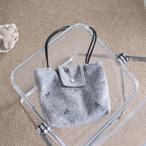 Detail of gray canvas tote with black bow embroidery and white button closure detail