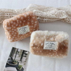 Detail of plush fawn print coin pouches with soft fur texture and woven rabbit labels