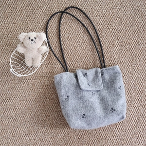 Close-up of canvas tote bag with bow embroidery and metal snap button closure