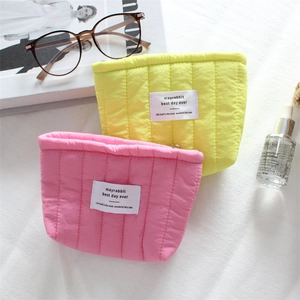 Close-up of quilted vertical striped cosmetic bags in pink and neon yellow