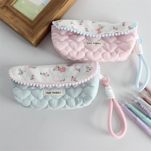 Quilted floral pencil case with heart texture and pom-pom trim in pink and blue