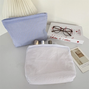 Detail view of blue striped and white seersucker cosmetic bags with seersucker texture