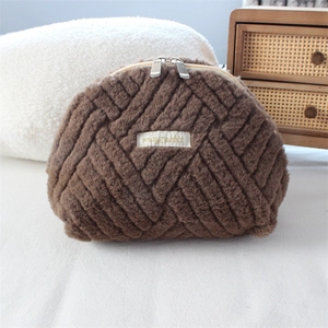 Detail of dark brown plush shell makeup bag with quilted texture and double zippers