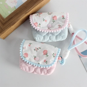 Detail of quilted floral pouch with puff edge trim and woven wrist strap for storage