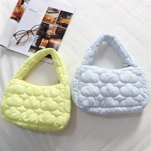 Detailed top view of light yellow and blue quilted puffer bags on a white surface
