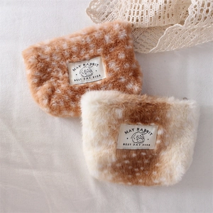 Detailed view of plush pouch with deer pattern texture and decorative brand logo tag