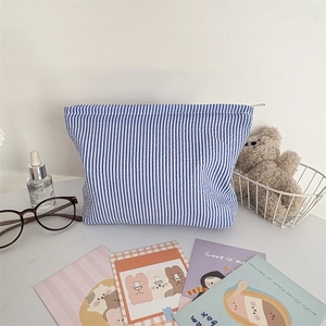 Detail of blue and white striped seersucker pouch with a smooth metal zipper closure