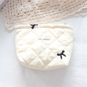 Detail of quilted cosmetic bag with black bow embroidery and woven brand label