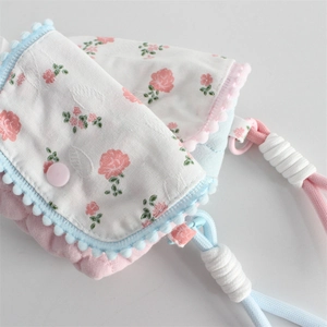 Close-up of quilted floral pencil case with pom-pom trim and adjustable lanyard strap