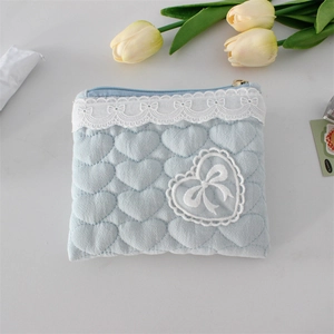 Détail d'une pochette matelassée bleu clair avec bordure en dentelle et broderie nœud