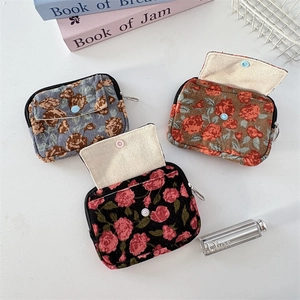 Detailed view of floral corduroy coin purses in blue, brown, and black with snap buttons