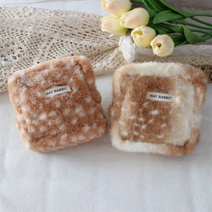 Close-up of plush fawn pattern makeup pouches with soft faux fur texture and brand labels