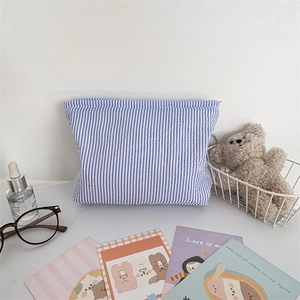 Detail of blue and white seersucker cosmetic bag with striped texture and zipper closure