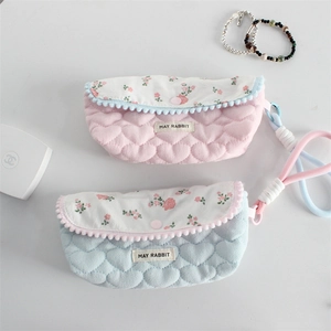 Detail of floral quilted pouches with scalloped edges and wrist straps in pink and blue