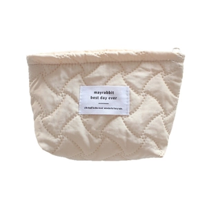 Quilted cream vanity pouch with vertical stitching and smooth metallic zipper closure