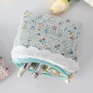 Detail of tweed coin purse showing lace trim, pearl zipper pull, and makeup storage