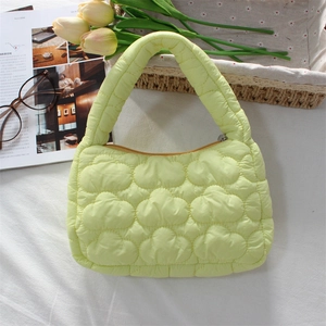 Detailed top view of light green quilted cloud handbag on a soft white fabric background