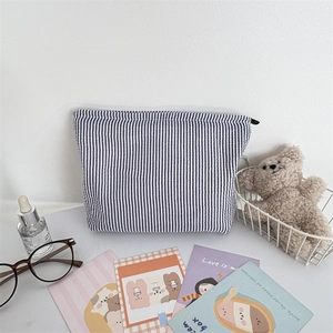 Detail of blue striped seersucker makeup bag with a smooth metal zipper closure