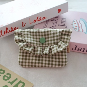 Detail of green gingham fabric storage pouch with ruffle trim and snap closure button