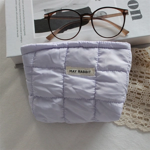 Detailed close-up of light purple quilted cosmetic bag with white brand label on top