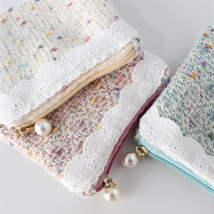 Detail of tweed coin purses with lace trim and elegant large pearl zipper pulls