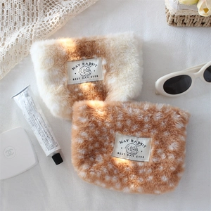 Close-up of soft plush cosmetic bags with deer pattern and rabbit woven label detail