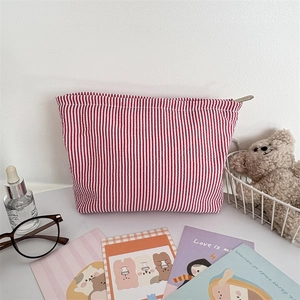 Detail of red and white striped seersucker makeup bag with a metal zipper closure