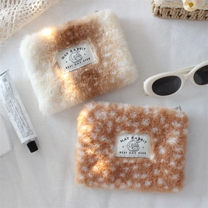 Detailed view of plush pouch with polka dot texture and canvas logo on white fabric
