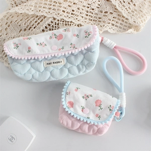 Detail of floral quilted pouches with heart textures and delicate pom-pom trim accents