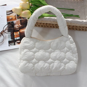 Detailed close-up of a white quilted puffer bag with cloud texture and top handle