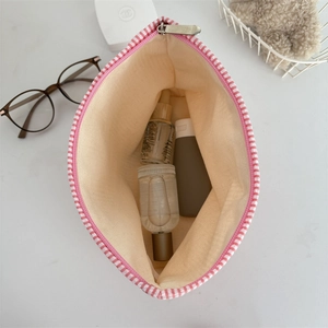 Detail view of pink striped seersucker makeup bag with spacious interior and metal zipper