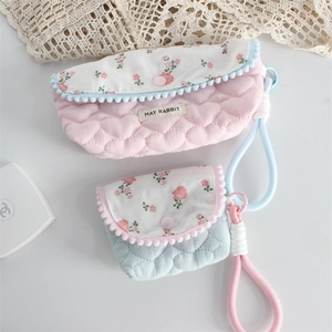 Detail of floral quilted storage bags with pom-pom trim and cotton wrist straps