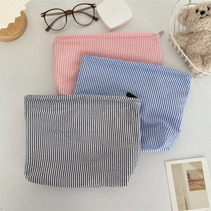 Three-piece seersucker cosmetic bag set with striped patterns and secure zip closure