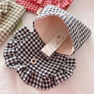 Detail of gingham mini storage bag showing metal snap closure and pink inner lining