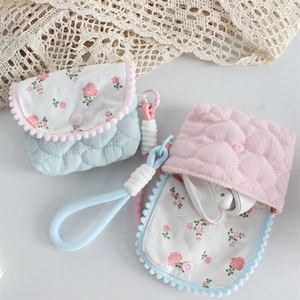 Detailed shot of quilted floral fabric pouch holding wireless earphones with strap