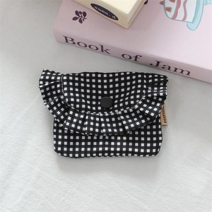 Detail view of mini black and white plaid storage bag with ruffle edge and button