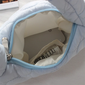 Macro view of blue quilted cloud bag showing spacious interior with white lining and zipper